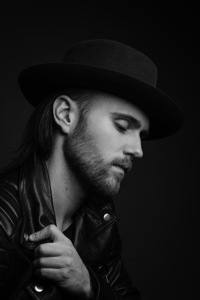 Black and white picture of Lukas Meijer, in a hat looking away from the camera